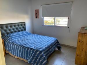 巴拉德罗Los Talares的一间卧室配有一张带蓝色棉被的床和窗户。