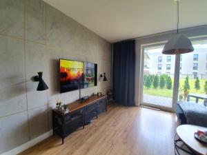 格丁尼亚Nadmorski apartament premium的客厅配有沙发和墙上的电视
