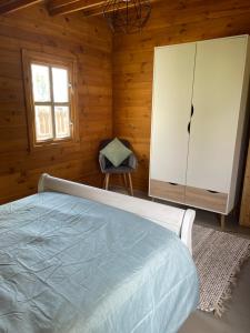 Marigny-lès-ReulléeDOMAINE DES GALLINACES CHALET SUSSEX 2-4p的卧室配有床、椅子和窗户。