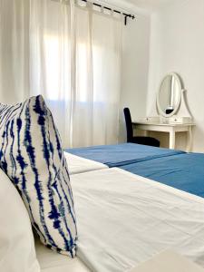 米尔芳提斯城Pirata Milfontes Guest House的一张带蓝色和白色毯子及镜子的床