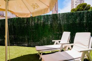 贝尼多姆Apartamento Loft con terreno privado y parking compartido - a 800m de Playa Poniente的围栏旁的两把椅子和一把伞