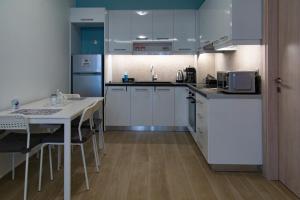海若克利欧Chelidoni apartment ground floor的厨房配有白色橱柜和带微波炉的桌子。