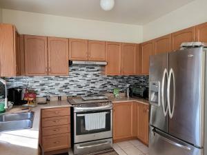 马卡姆Extended Stays Home的厨房配有木制橱柜和不锈钢冰箱。