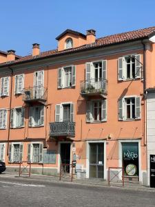 比耶拉Il Giardino Segreto的一座橙色的建筑,设有白色的窗户和阳台,位于街道上