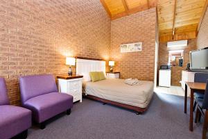 比奇沃斯比奇沃思车厢汽车旅馆的一间卧室配有一张床和两张紫色椅子