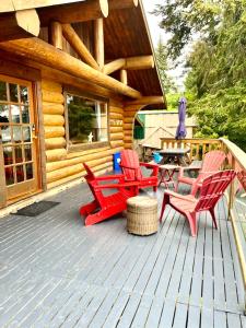 Gillies BayThe Beach House Texada - Waterfront Cabin的小屋内带红色椅子和野餐桌的甲板