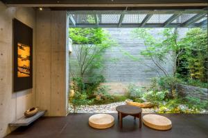 京都Genji Kyoto, a Member of Design Hotels的花园前设有2张桌子和2把凳子的房间