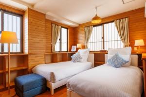 那霸Naha Gajumaru Apartment Hotel 401的配有木墙和窗户的客房内的两张床