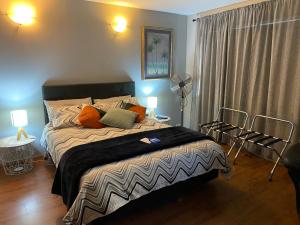 奥克兰Opanuku Out West的一间卧室配有一张大床和风扇