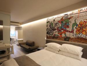 特拉维夫Link Hotel & Hub By Dan Hotels的酒店客房,设有床铺和带壁画的墙壁