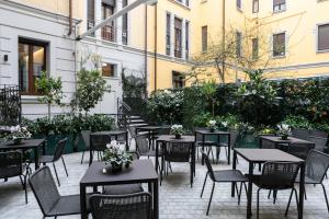 米兰Ariosto Social Club的户外庭院设有桌椅和植物