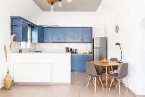 皮尔戈斯Ampelos Executive Houses的厨房配有蓝色橱柜和桌椅