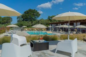 Montecorvino PuglianoTerra di Vento的一个带白色椅子和遮阳伞的庭院和一个游泳池