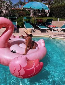 丰达切洛Villa Grazia的坐在游泳池中粉红色木筏上的戴帽子的女人