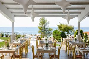 尼坡帝伊斯申俱乐部Spa酒店的餐厅设有桌椅,以大海为背景