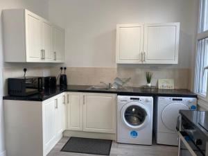 莱斯特De Luxe Aparthotel的厨房配有白色橱柜和洗衣机。