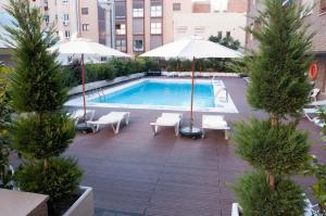 马德里胡安布拉沃公寓的城市里一个带椅子和遮阳伞的游泳池