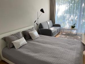 派尔努Lovely Aisa studio in Pärnu的一间卧室配有一张床、一张沙发和一把椅子
