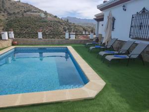 托罗克斯Casa rural Villa Miradri的草坪上的游泳池,周围摆放着椅子