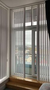 拉恩3 Bedroom Penthouse Apartment in larne的客房设有带白色百叶窗的大窗户。