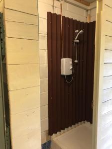 斯托马基特The Kestrel Shepherd Hut, Whitehouse Farm的浴室设有棕色墙壁和淋浴。
