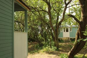 斯托马基特The Tawny Shepherd Hut, Whitehouse Farm的绿色房子,有白色的栅栏和树木