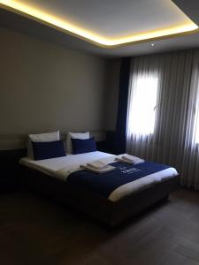 乌宗Kibar Suite Hotel的一间卧室配有一张带蓝色床单的床和一扇窗户。