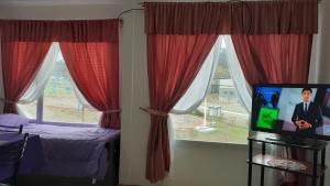乌斯怀亚Mono ambiente el mirador的一间卧室设有红色窗帘和一台电视机的窗户。