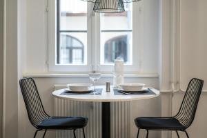 卢布尔雅那Strict city apartments的一张带两把椅子的白色桌子和一扇窗户