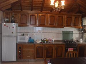CalhetaAdega do Batista的厨房配有木制橱柜和白色冰箱。