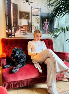 TofteVilla Utsikten的坐在红色沙发上的女人,带着黑狗