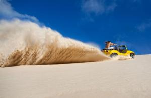 纳塔尔纳塔尔假日酒店的一个人在沙子里骑着一辆黄色吉普车