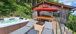 InnerschwandRuhige Bergvilla in Alleinlage am Mondsee mit Seeblick Bergblick und Whirlpool的甲板上设有热水浴池和红色遮阳伞