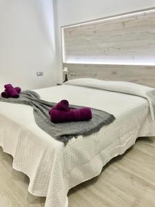 阿罗纳ISLAND SUITES的一间卧室配有一张带紫色毛巾的床