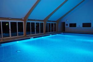 帕兹托Retallack Resort 4 bedroom lodge - Hot Tub for hire on request -Pool & Spa的大楼内带蓝色灯光的游泳池