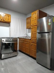 华雷斯城Casa M&J Cd. Juarez的厨房配有不锈钢冰箱和木制橱柜
