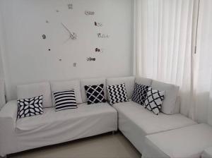 塔克纳Apartamento Amoblado en Tacna的白色沙发,上面有枕头,墙上有时钟