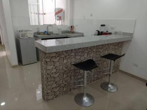 塔克纳Apartamento Amoblado en Tacna的厨房配有带2把吧台凳的石台