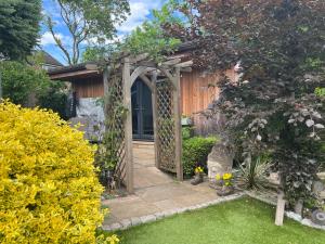 赫默尔亨普斯特德Thistle Lodge - Quiet Garden lodge with off road parking的一个带凉亭的花园和一个房子的入口