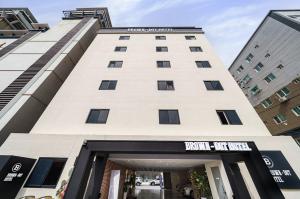 仁川市Brown-Dot Hotel Geomdan的一座高大的白色建筑,上面有标志