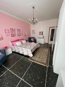 塞拉瓦莱·斯克里维亚Casa Adele的粉红色的卧室配有一张床和吊灯