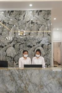 顺化Nhật Phương Hotel的两名妇女戴面具在电脑前
