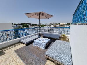 西迪·布·赛义德Cosy 1bdr, with a terasse in heart of Sidibou的阳台的天井配有桌子和遮阳伞。