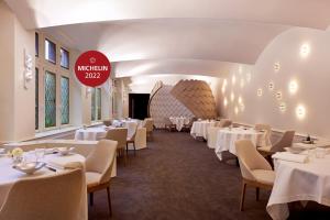 科尔马Relais & Châteaux La Maison Des Têtes的一间设有白色桌椅和标志的餐厅