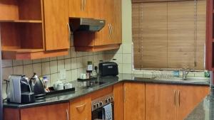 比勒陀利亚Homely Apartment, Hatfield, Unit-9的一个带木制橱柜和水槽的厨房
