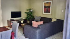 比勒陀利亚Homely Apartment, Hatfield, Unit-9的客厅配有蓝色的沙发和电视