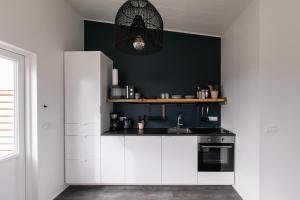 Sandgerði桑德格迪小屋酒店的厨房配有白色橱柜和黑色墙壁
