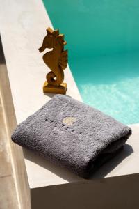 佩里沃罗Kasteli Suites的坐在泳池旁的桌子上的一个毛巾