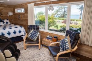 塞奎姆Dungeness Bay Cottages的一间卧室配有一张床、两把椅子和一个窗户