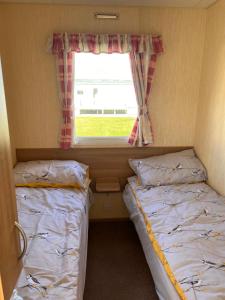 阿贝尔格莱Evans Whitehouse Caravan Towyn的小型客房 - 带2张床和窗户